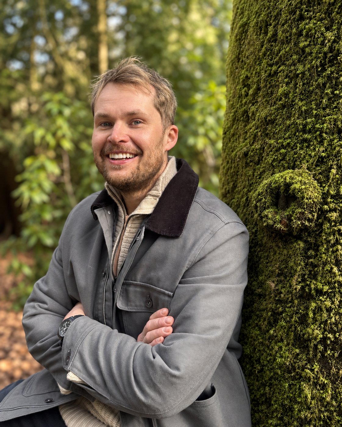Ian Collier beside a moss-covered tree in woodland
